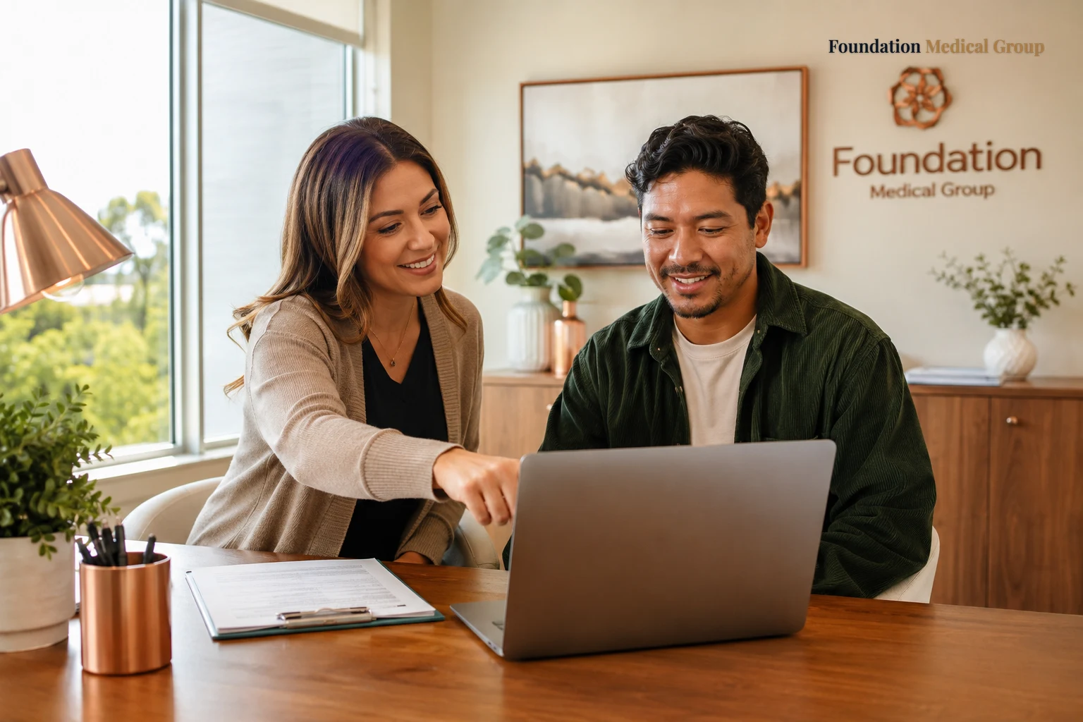 A caring coordinator and a patient look together at a laptop screen, the coordinator pointing encouragingly as morning l